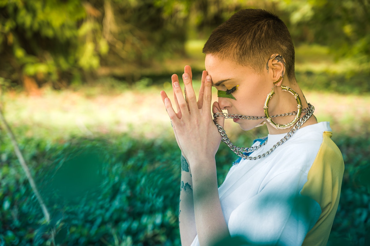 A young woman holding up her hands in prayer signifying belief