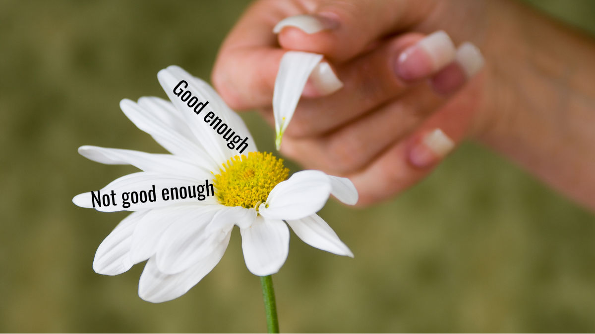 A woman picking petals off a daisy. The petals are labelled "good enough" and "not good enough"